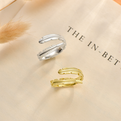 Silver and gold feather rings on a book page