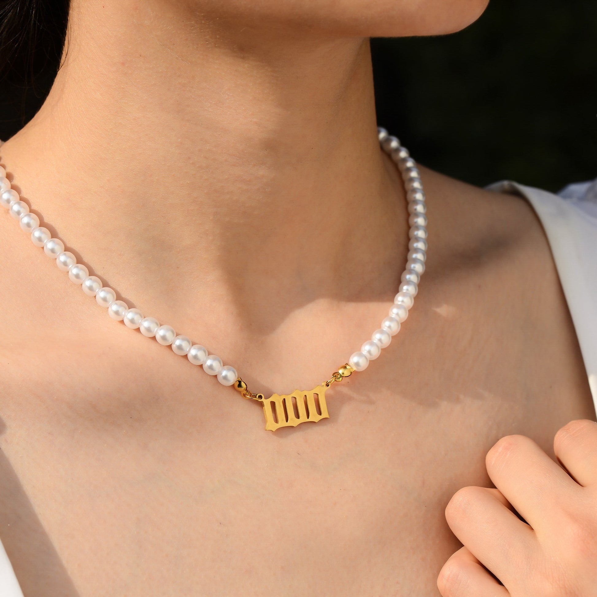 Pearl necklace with gold three zero digits pendant worn by a young female