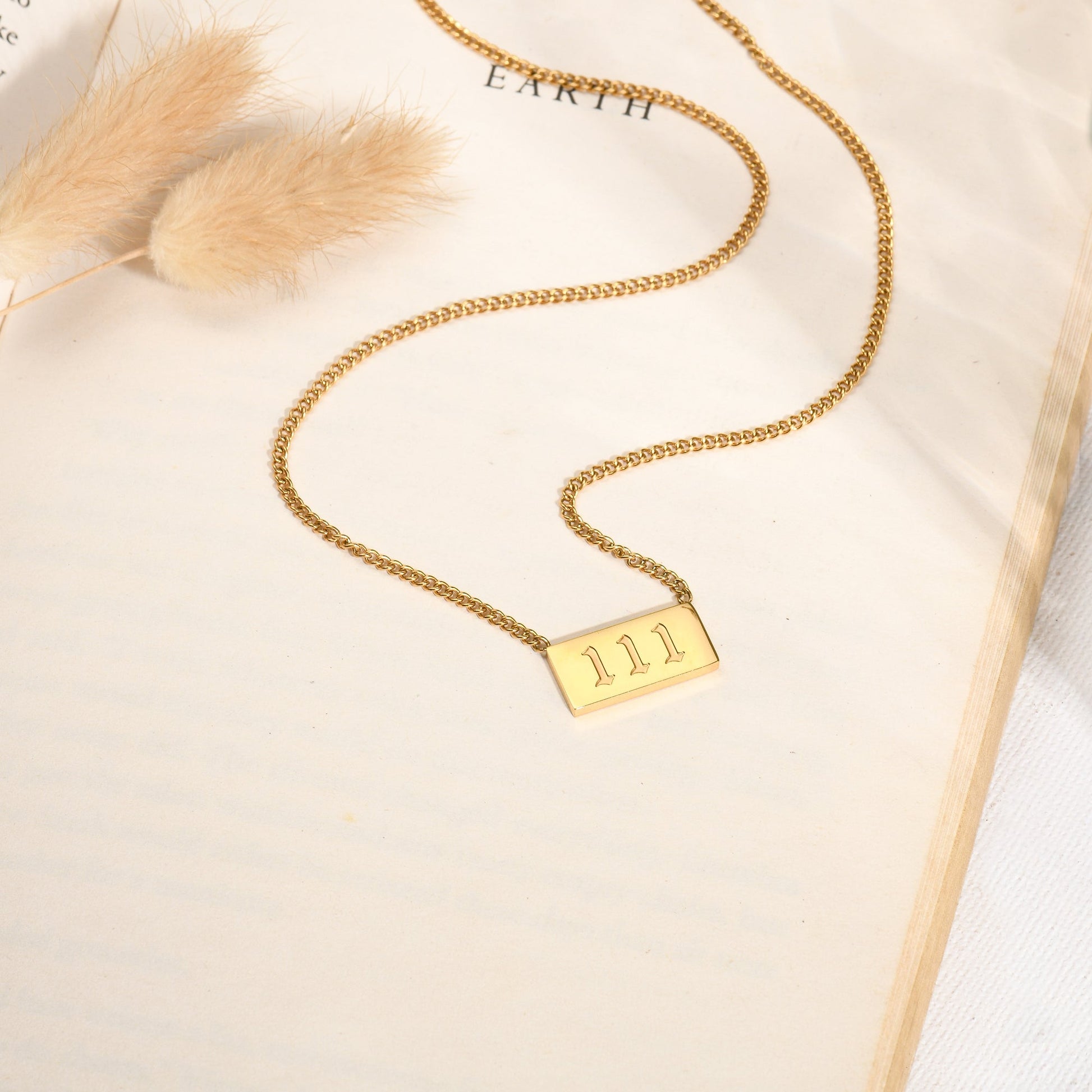 Gold chain necklace with angel number 111 pendant on a book page