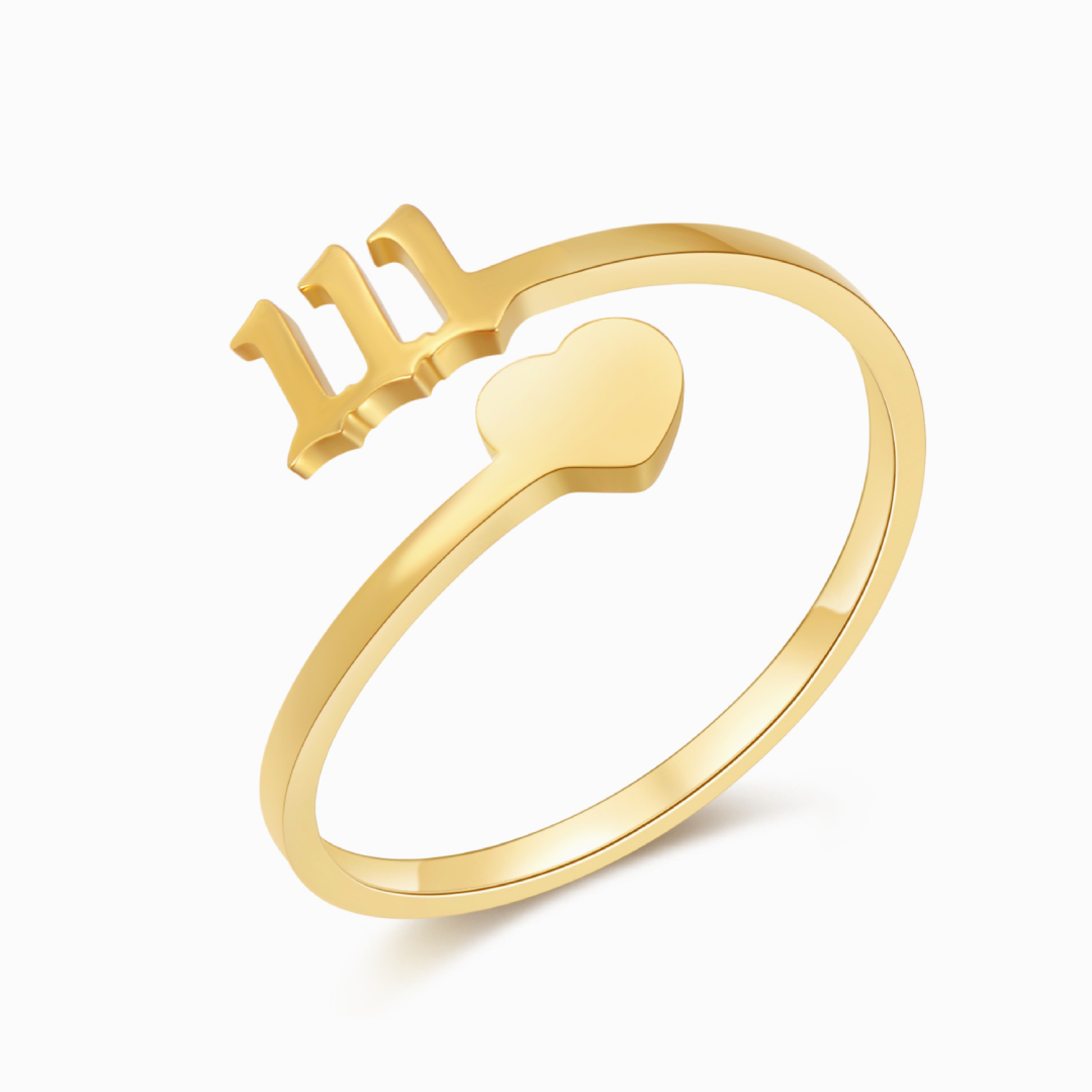 Gold ring with angel number 111 and heart charm on white background