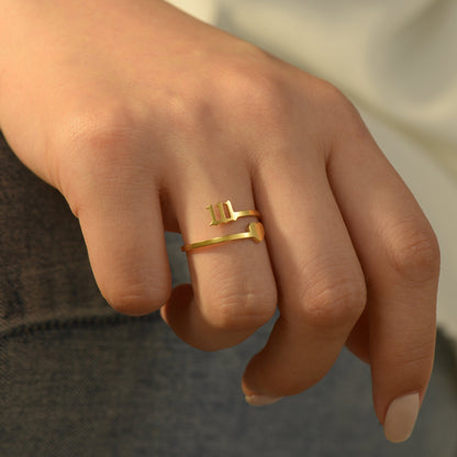 Gold ring with angel number 111 and heart charm on woman's ring finger