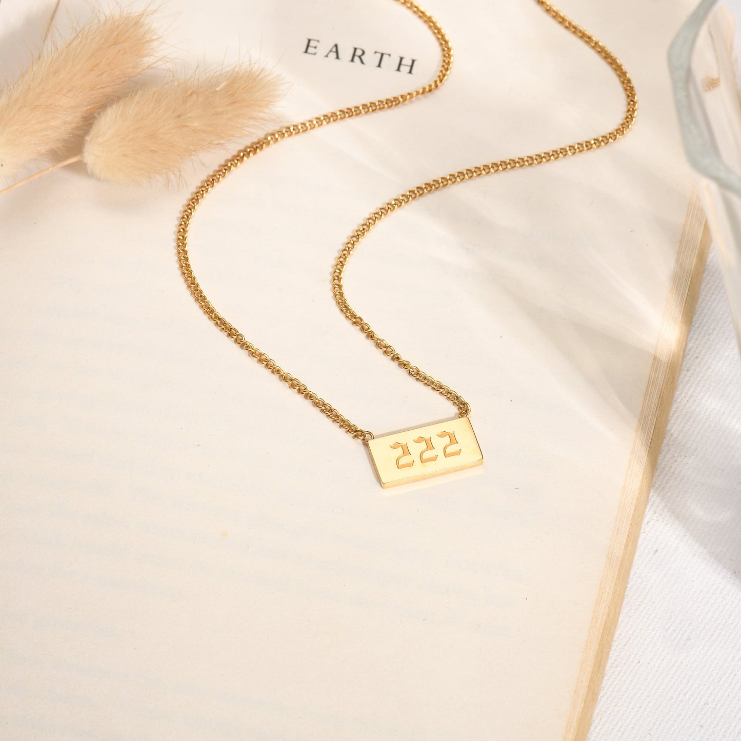 Gold chain necklace with angel number 222 pendant on a book page