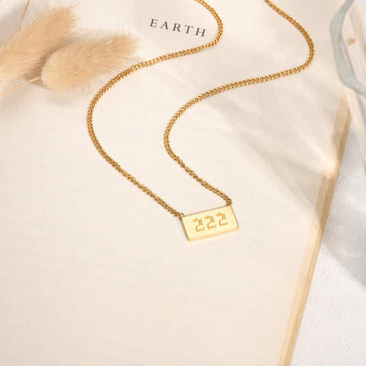 Gold chain necklace with angel number 222 pendant on a book page