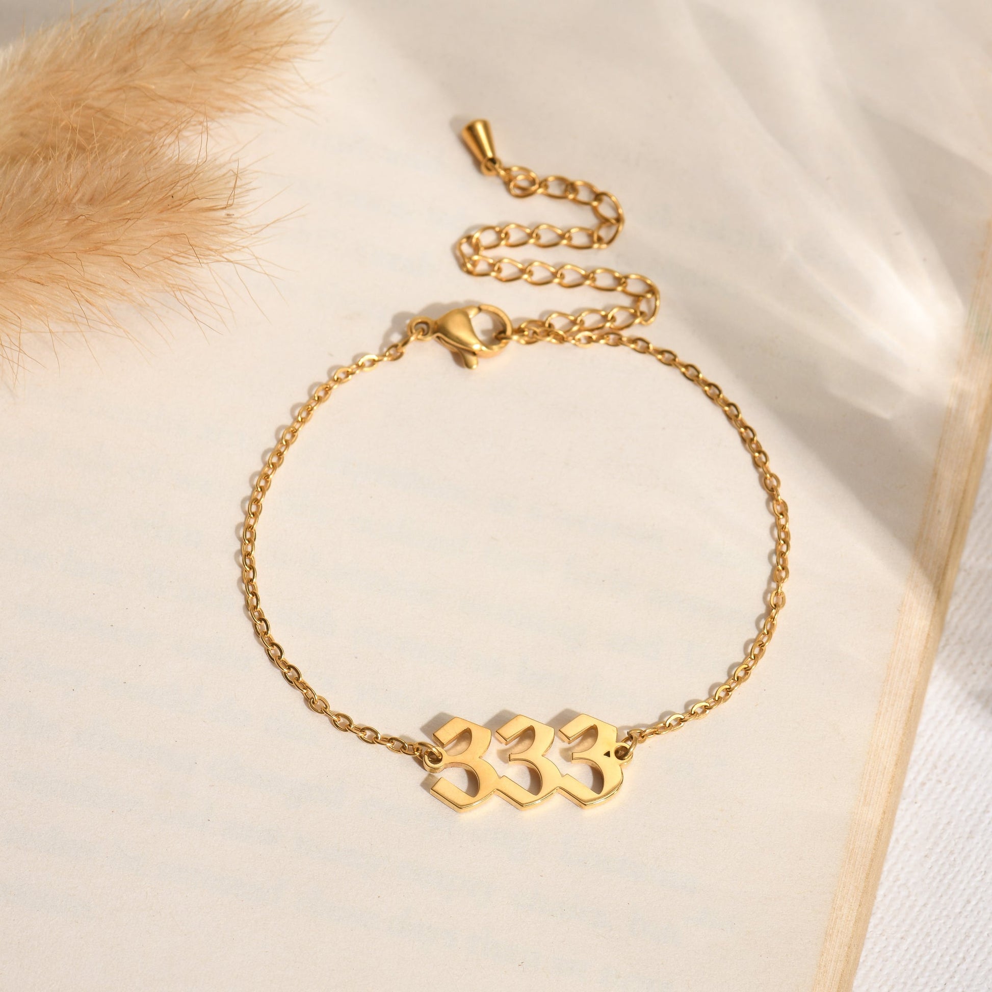 Gold angel number 333 bracelet on a book page