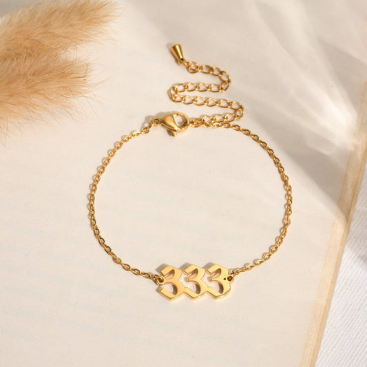 Gold angel number 333 bracelet on a book page