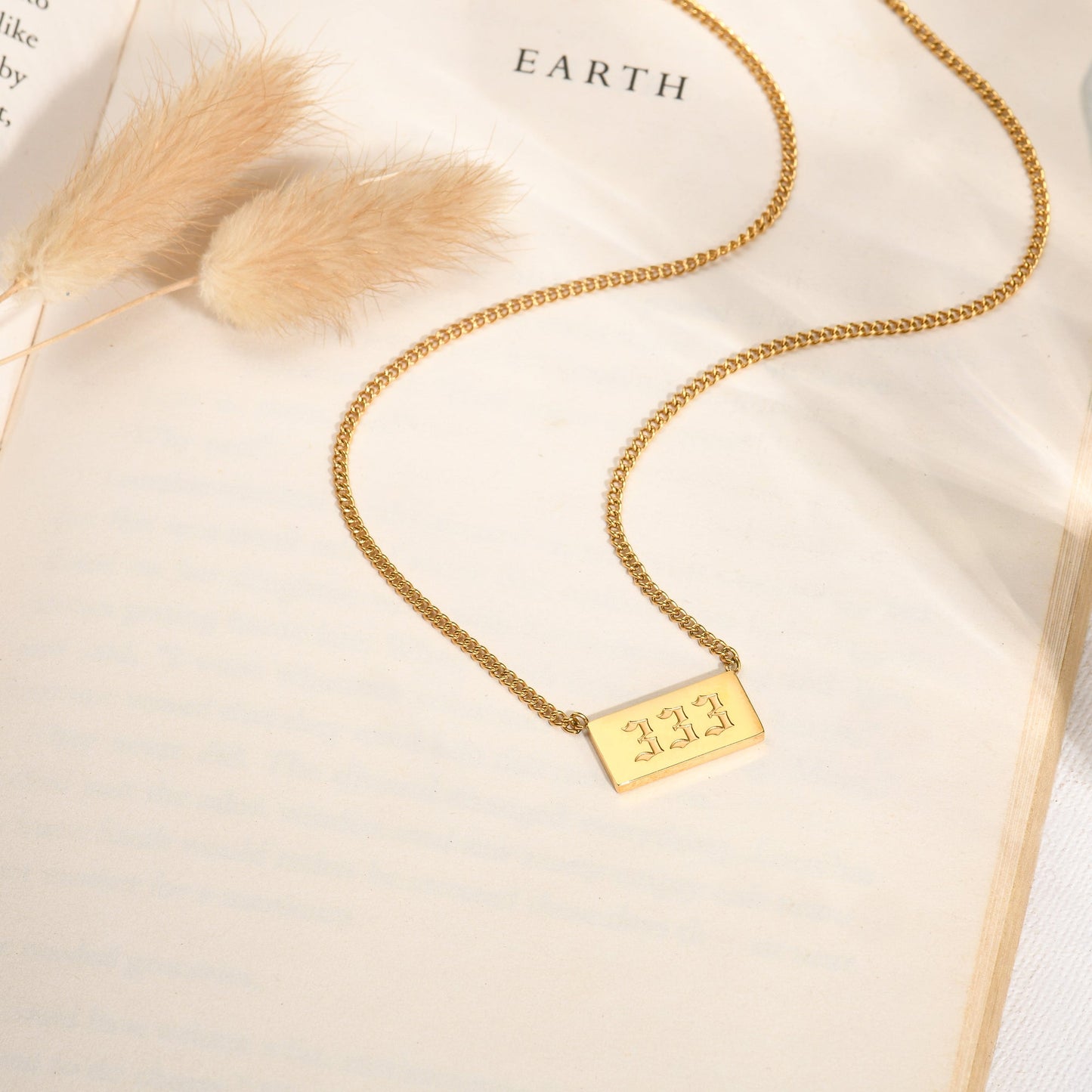 Gold chain necklace and angel number 333 on a book page