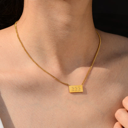 Gold chain necklace and angel number 333 worn by a young woman