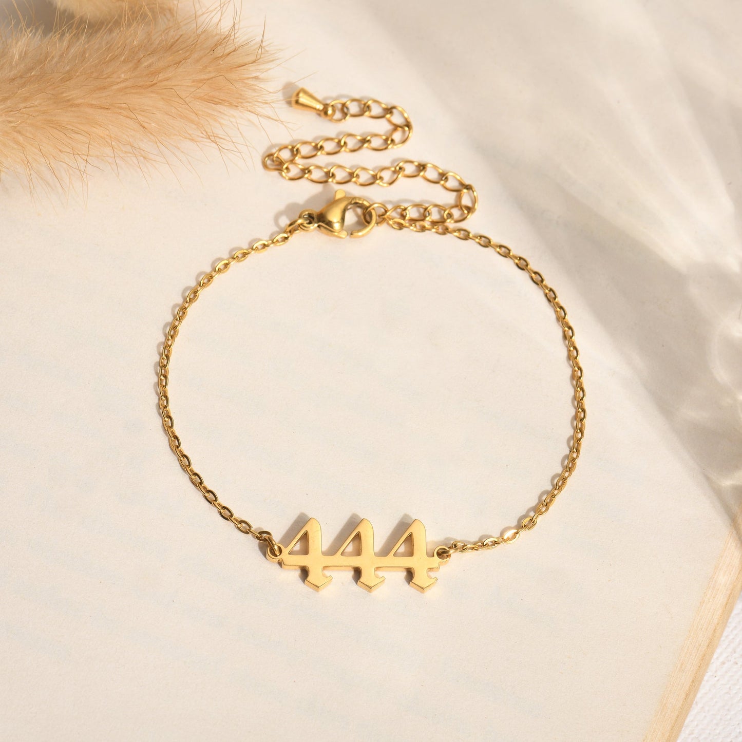 Gold bracelet with angel number 444 on a book page