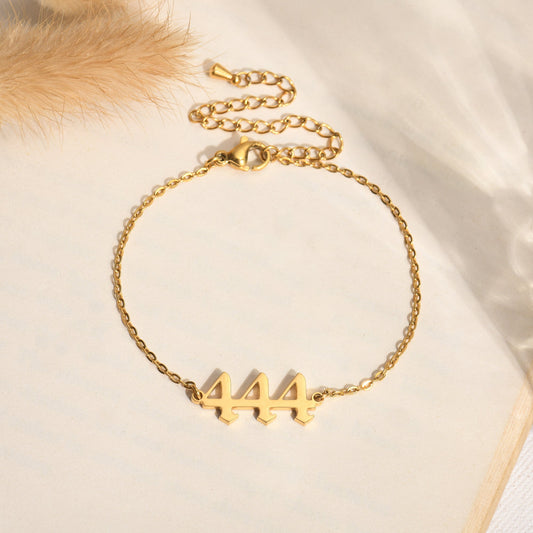 Gold bracelet with angel number 444 on a book page