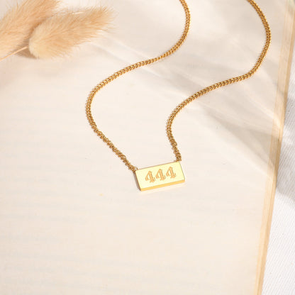 Gold necklace with angel number 444 pendant on a bookpage with floral background