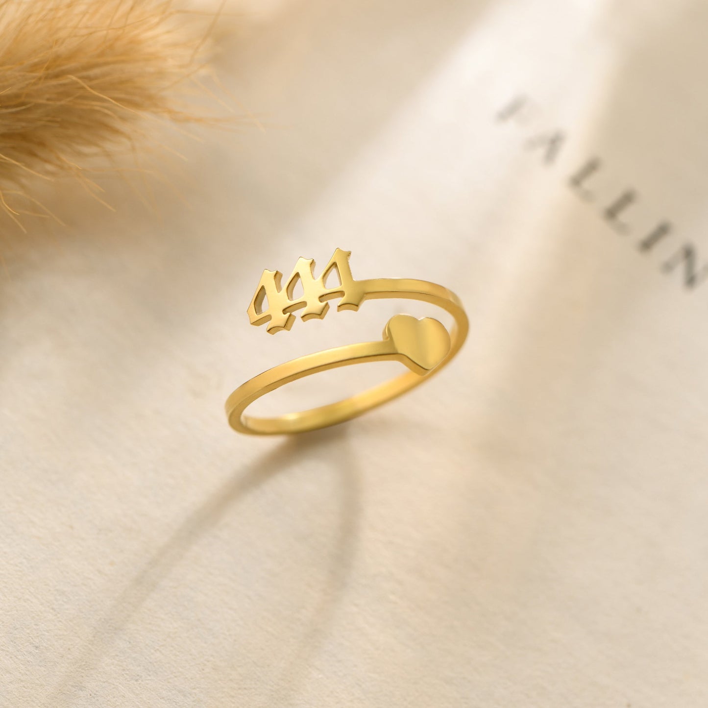 A gold ring with angel number 444 and a heart symbol on a bookpage