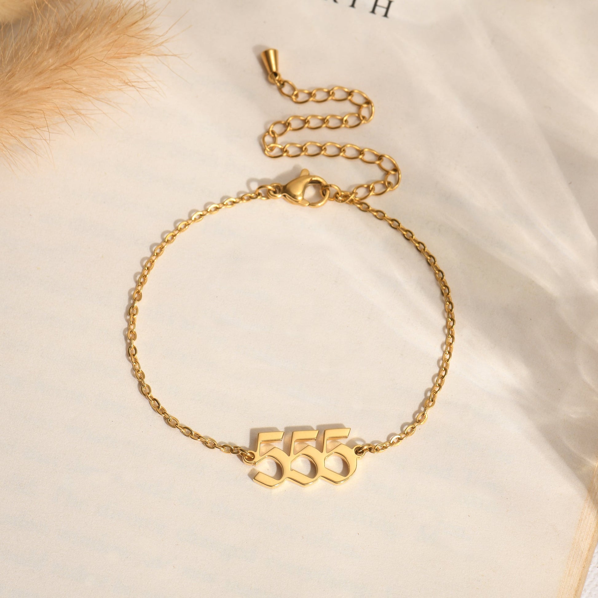 Gold bracelet with angel number 555 on a book page