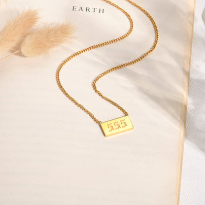 Gold chain necklace with gold angel number 555 pendant on a book page