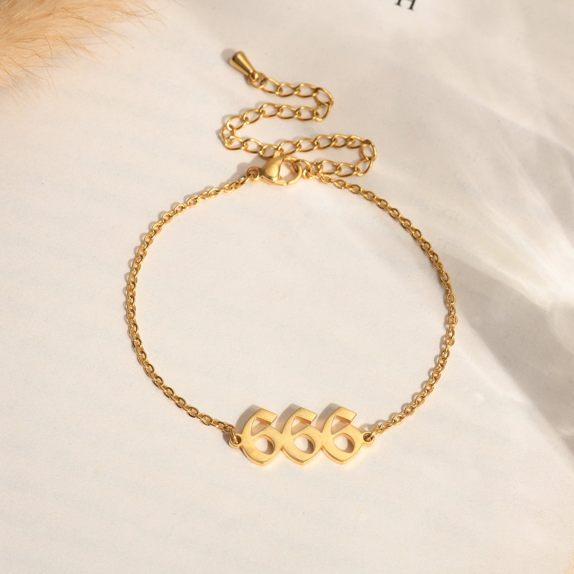 Gold bracelet with angel number 666 on a book page