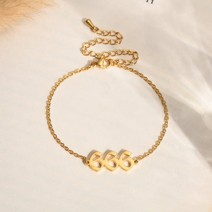 Gold bracelet with angel number 666 on a book page