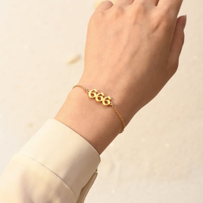 Gold bracelet with angel number 666 on woman's wrist