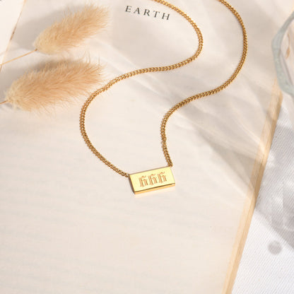 Gold chain necklace with gold angel number 666 pendant on a book page