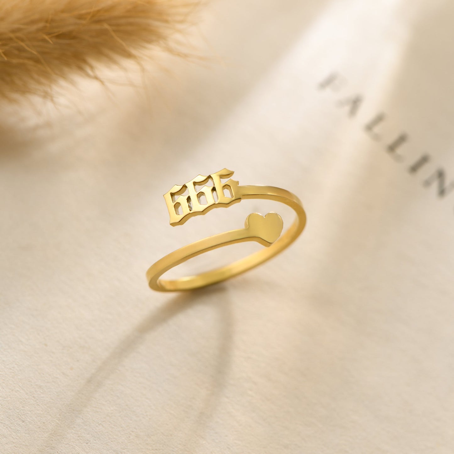 A gold ring with angel number 666 and  heart symbol on a bookpage