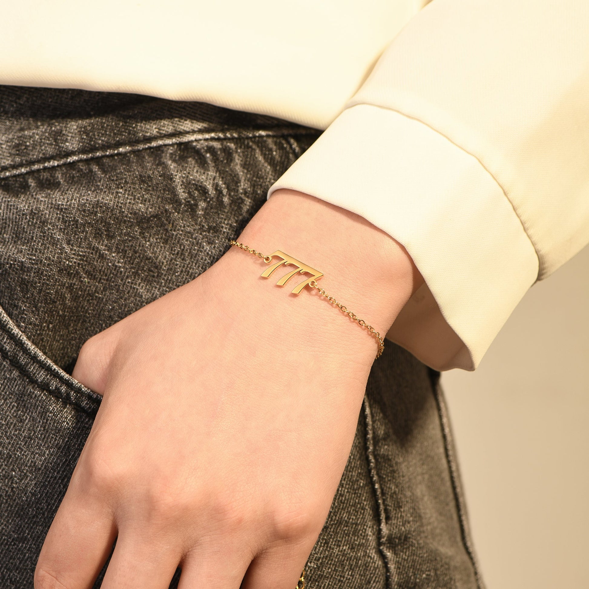 Gold bracelet with gold angel number 777 on woman's wrist