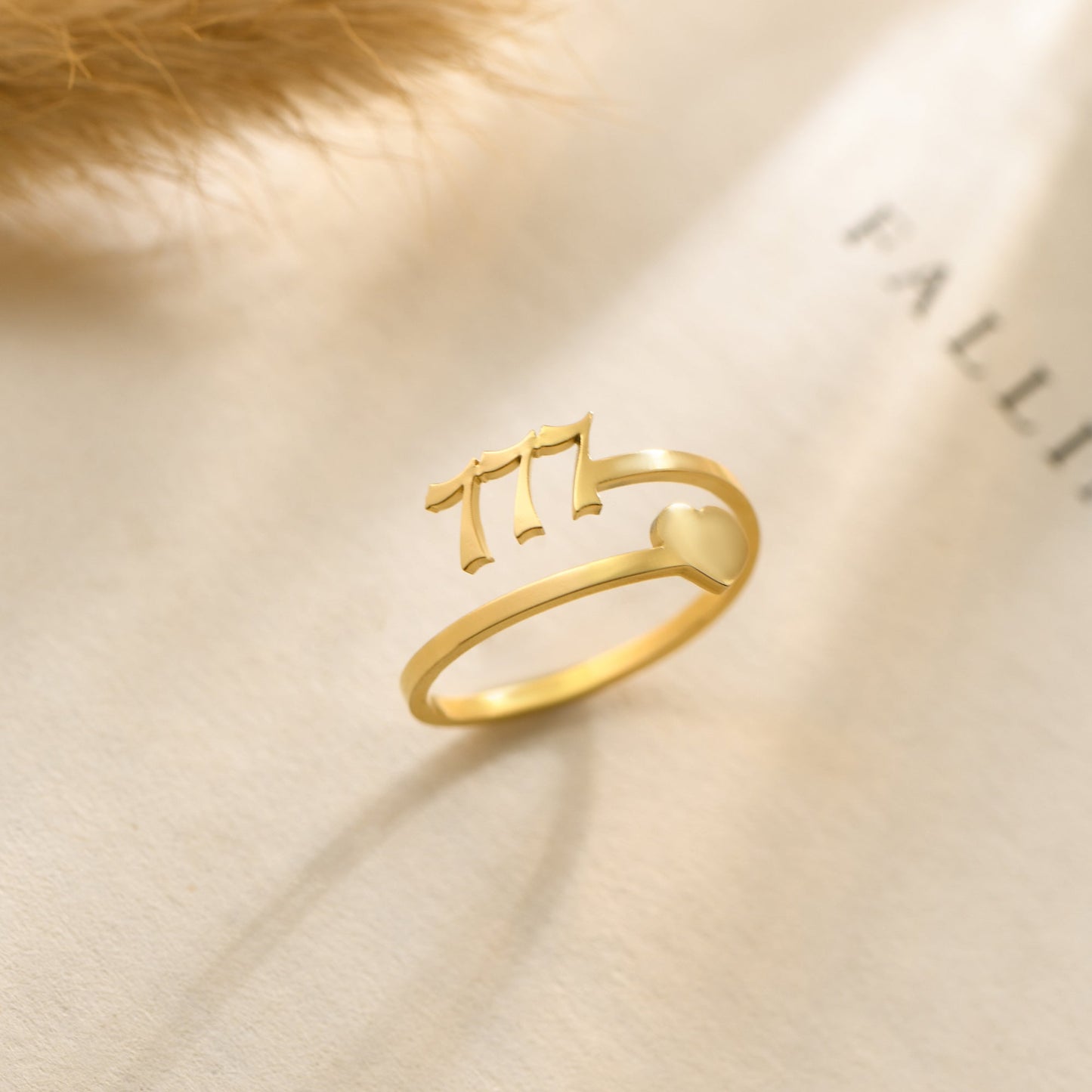 A gold ring with angel number 777 and heart symbol on a bookpage