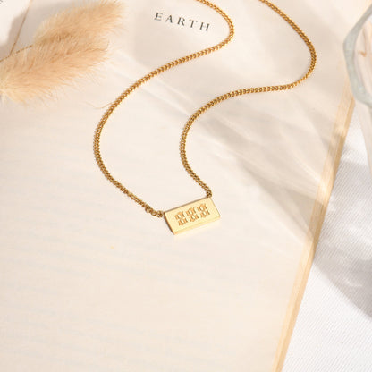 A gold chain necklace with angel number 888 pendant on a bookpage