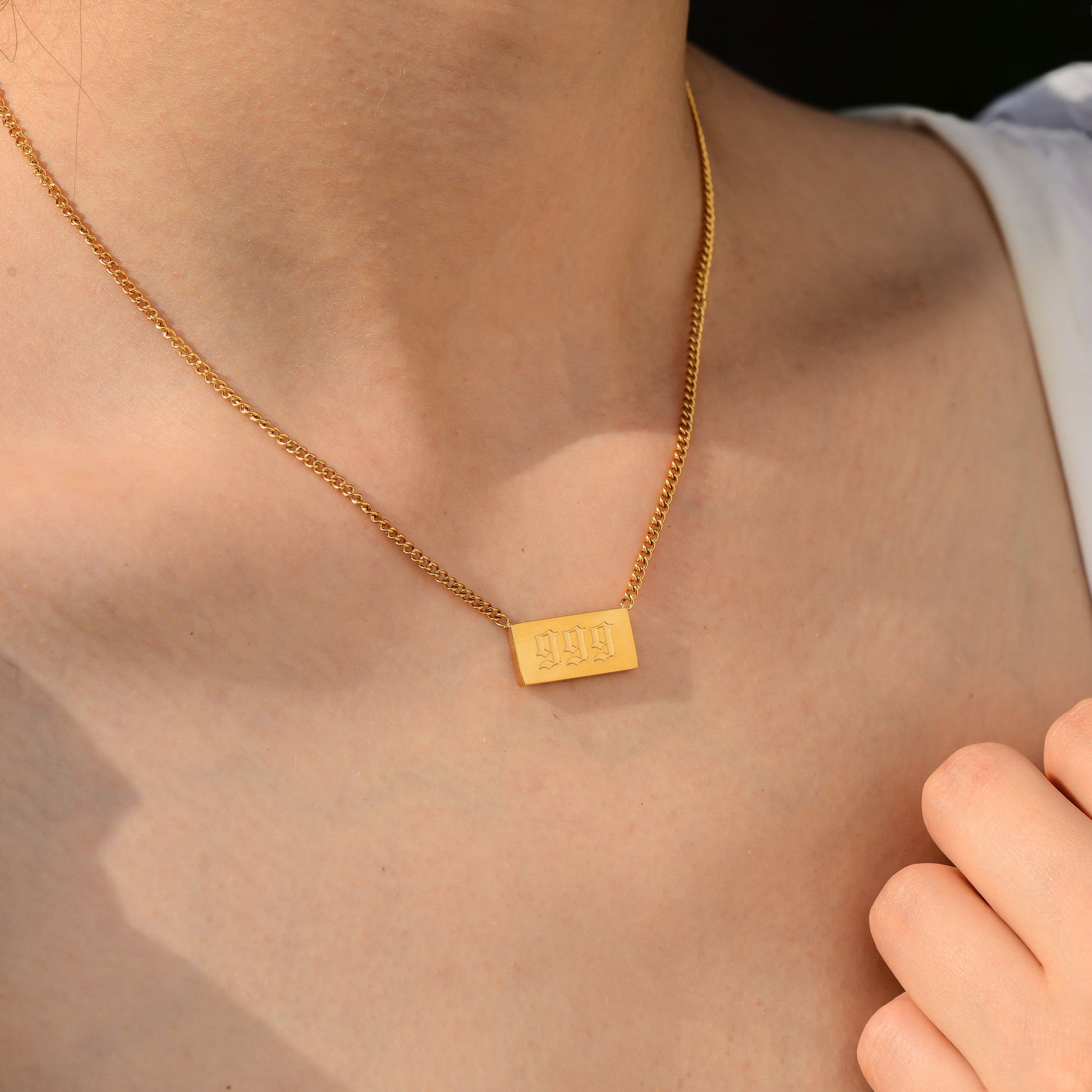 Gold chain necklace with angel number 999 worn by a woman