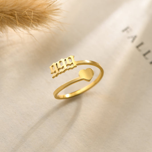 A gold ring with angel number 999 and heart symbol on a white bookpage