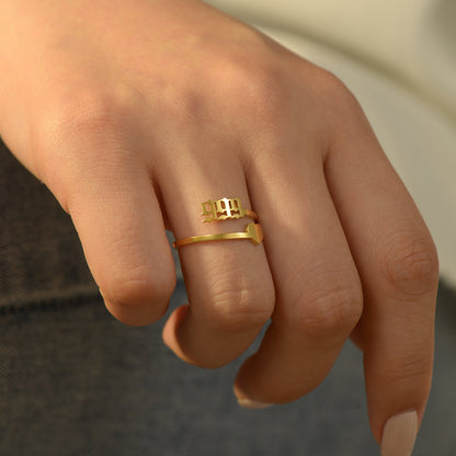 A gold ring with angel number 999 and heart symbol on a woman's ring finger