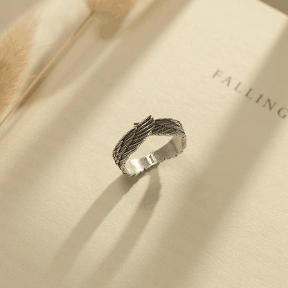 Silver angel wings ring engraved with angel number on a book page