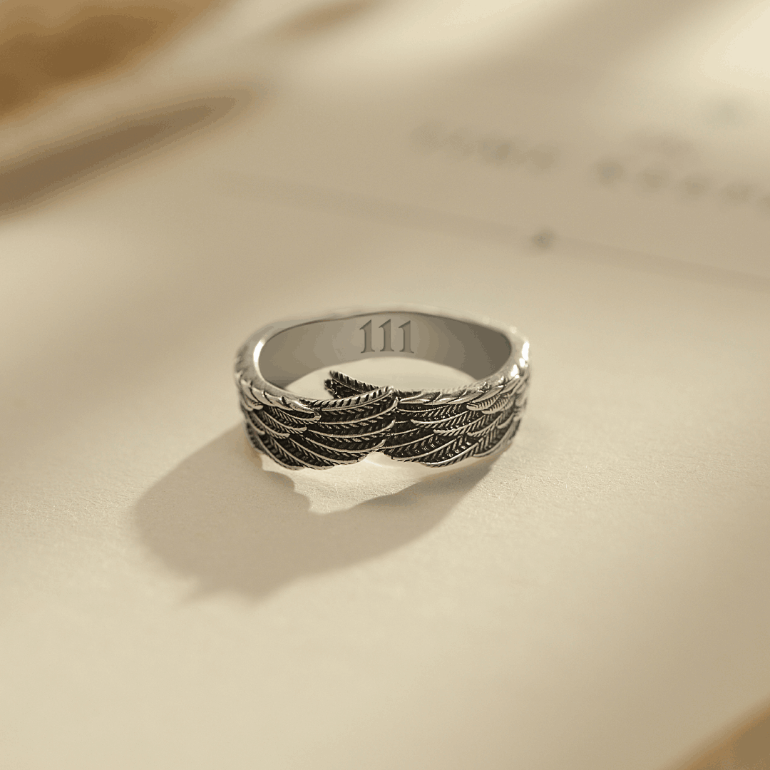 Silver wings ring engraved with angel number on a book page