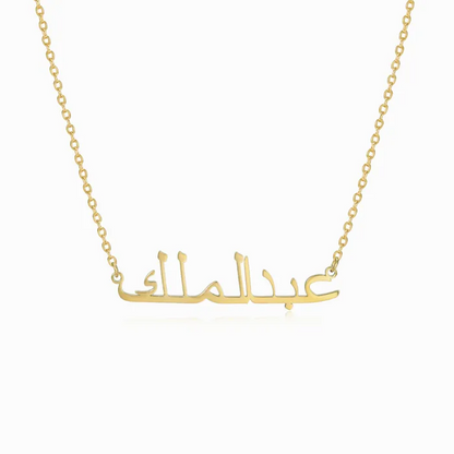 Gold necklace with Arabic engraved name on white background.