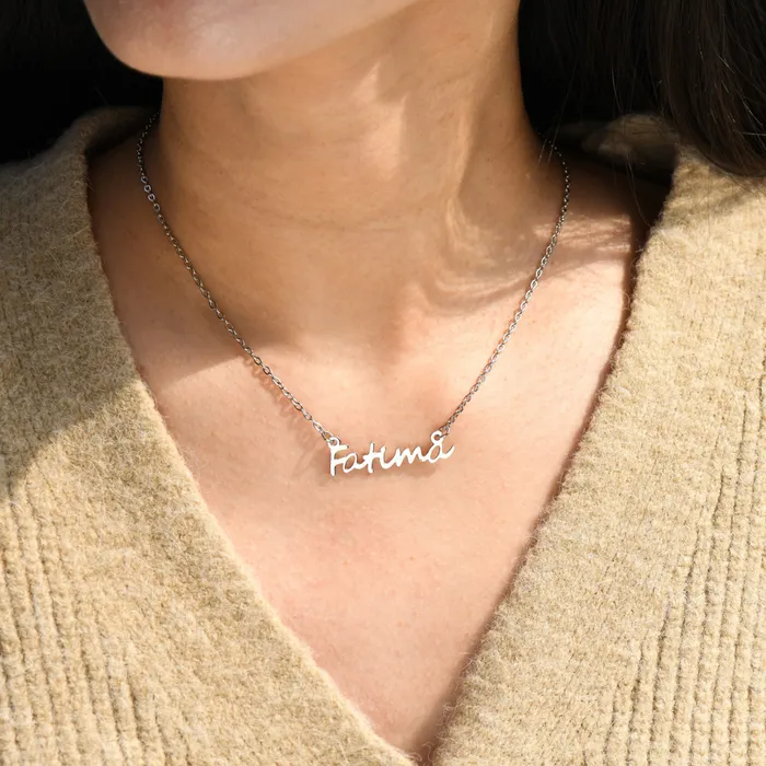 Woman in beige knitted top wearing a silver engraved necklace "Fatima".