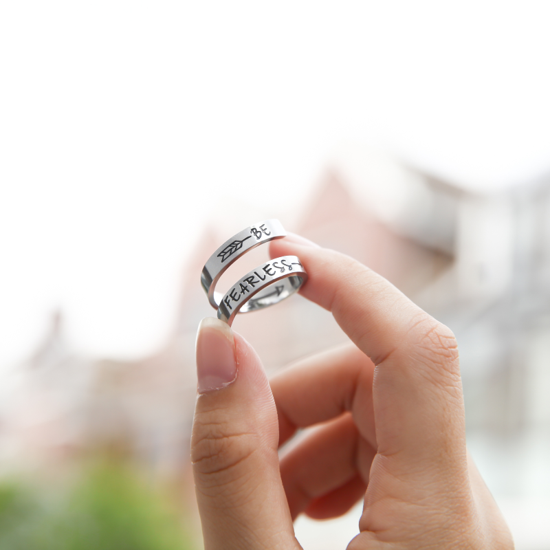 A silver twisted ring with text engraving held by female's hand