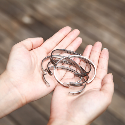 Silver bracelets engraved with texts on female's hands