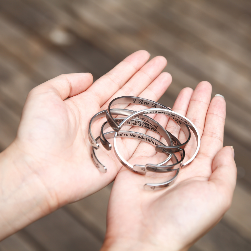 Silver bracelets with text engraving on female's hands