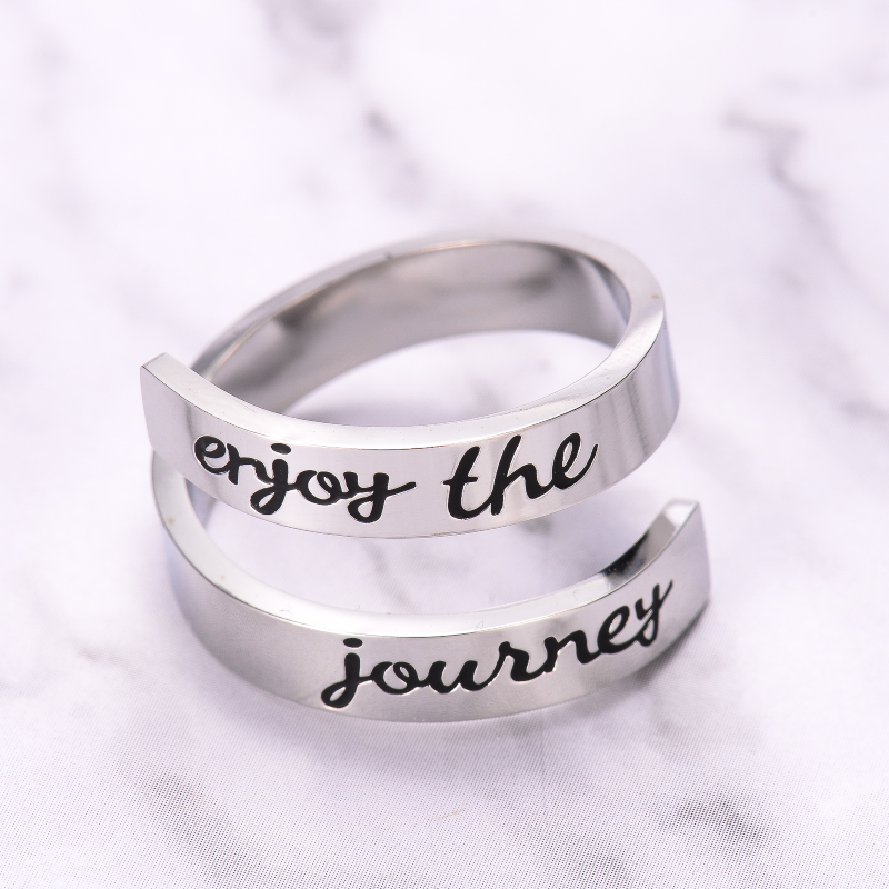 Silver twisted ring with text engraving on marble background