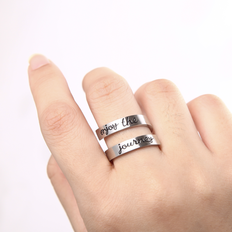 Silver twisted ring with text engraving on female's middle finger