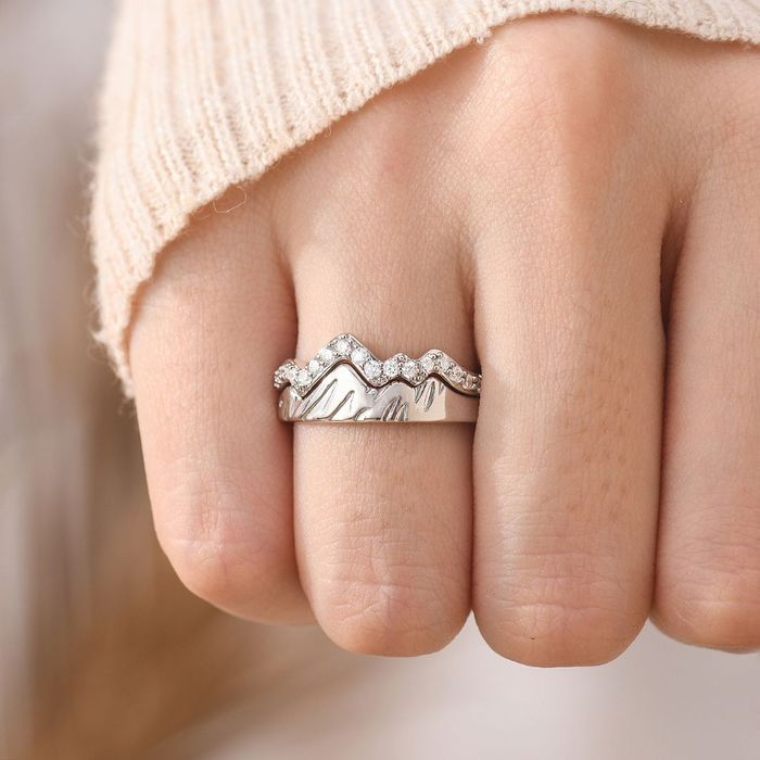 silver mountain rings with small stones stack together on a woman's ring finger