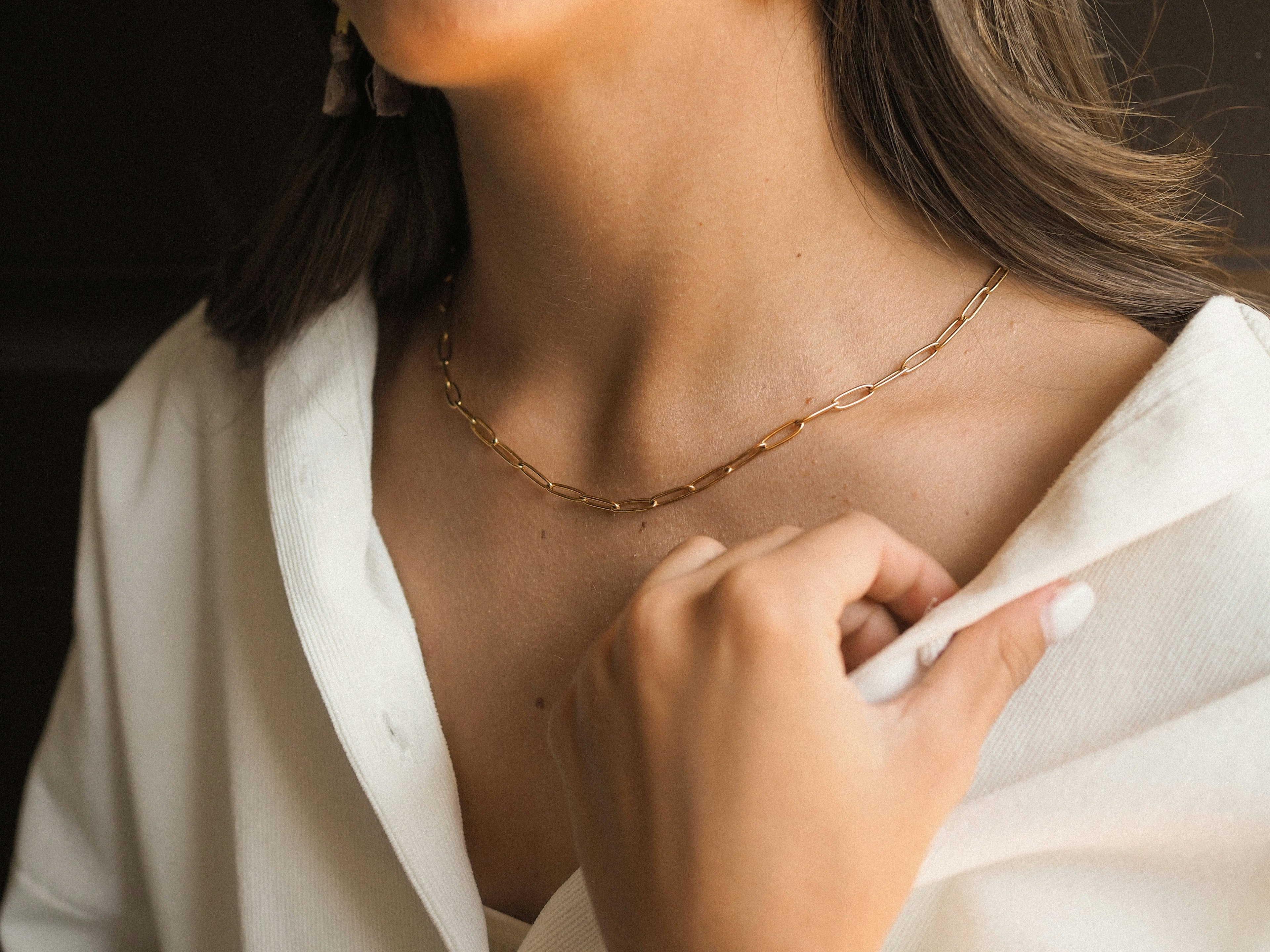 woman in white top wearing a gold chain necklace