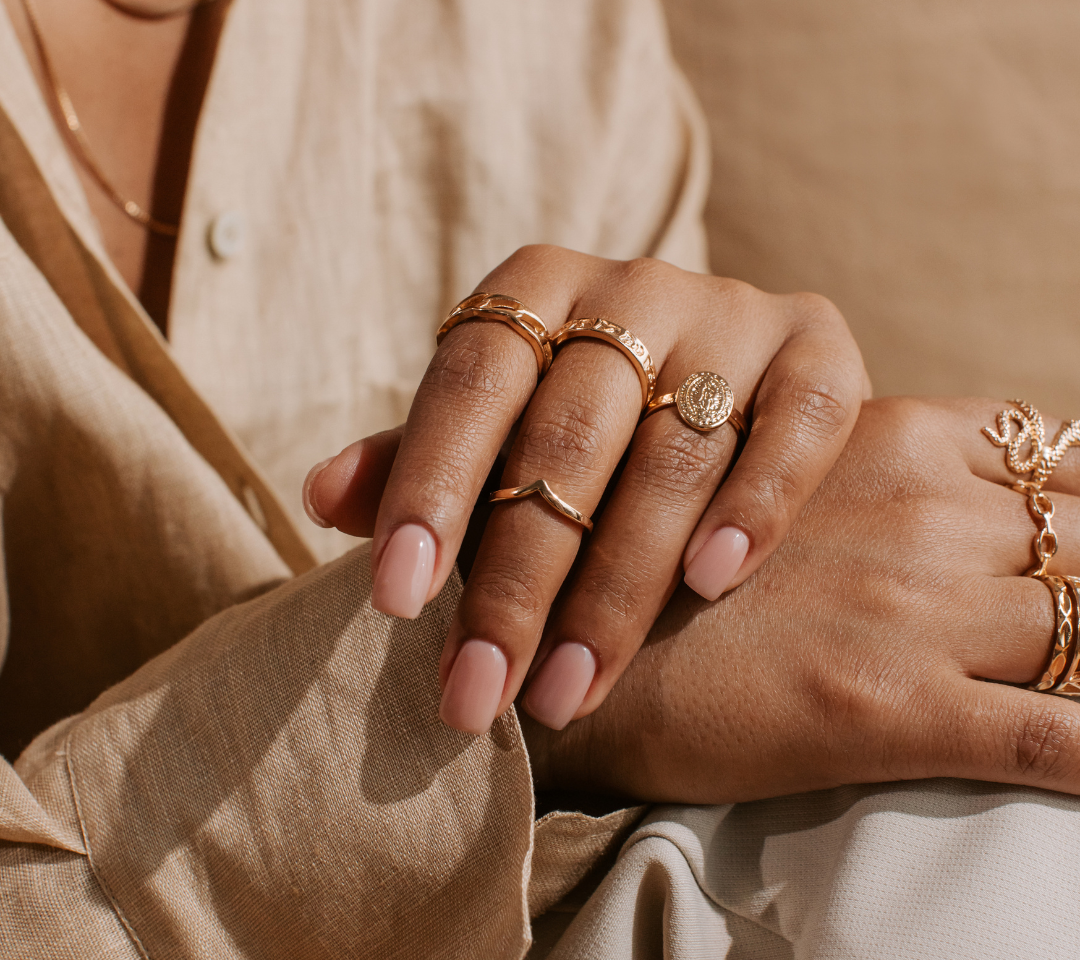 woman in beige long sleeve wearing a few gold rings 