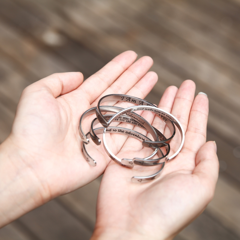 Silver bracelets with text engraving on female's hand