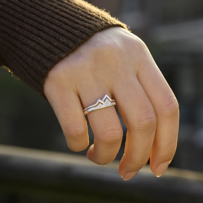 A female's hand wearing a silver mountain ring with stones on her ring finger.