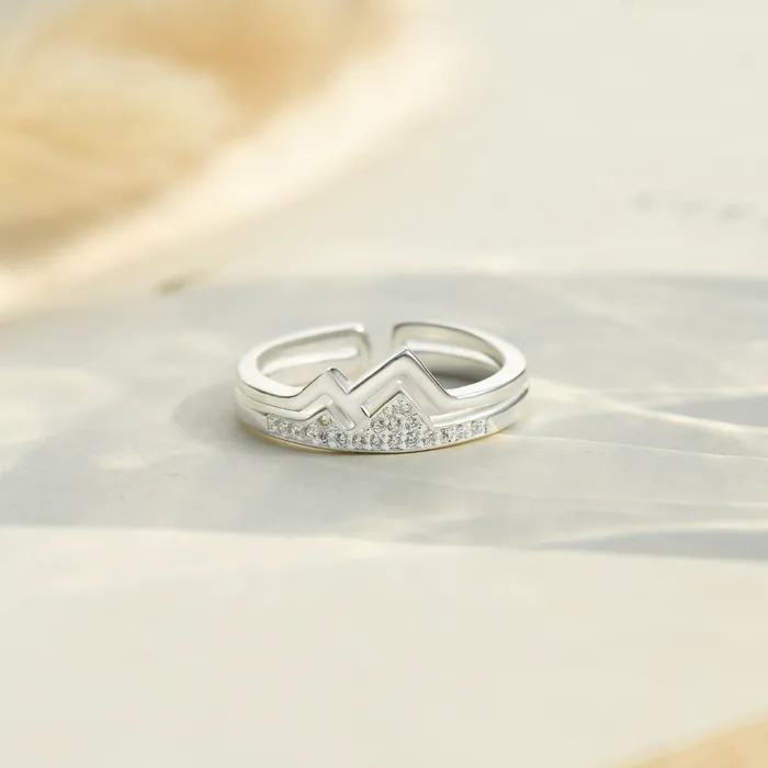 A silver mountain ring with stones on a light background