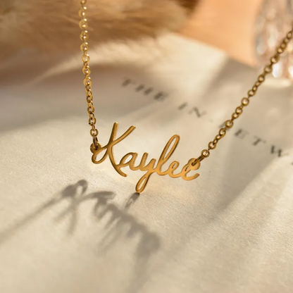 A personalized gold name necklace on a book page and a floral background