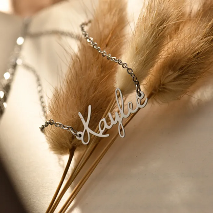 A personalized silver name necklace "Kaylee" on feather-like leaves