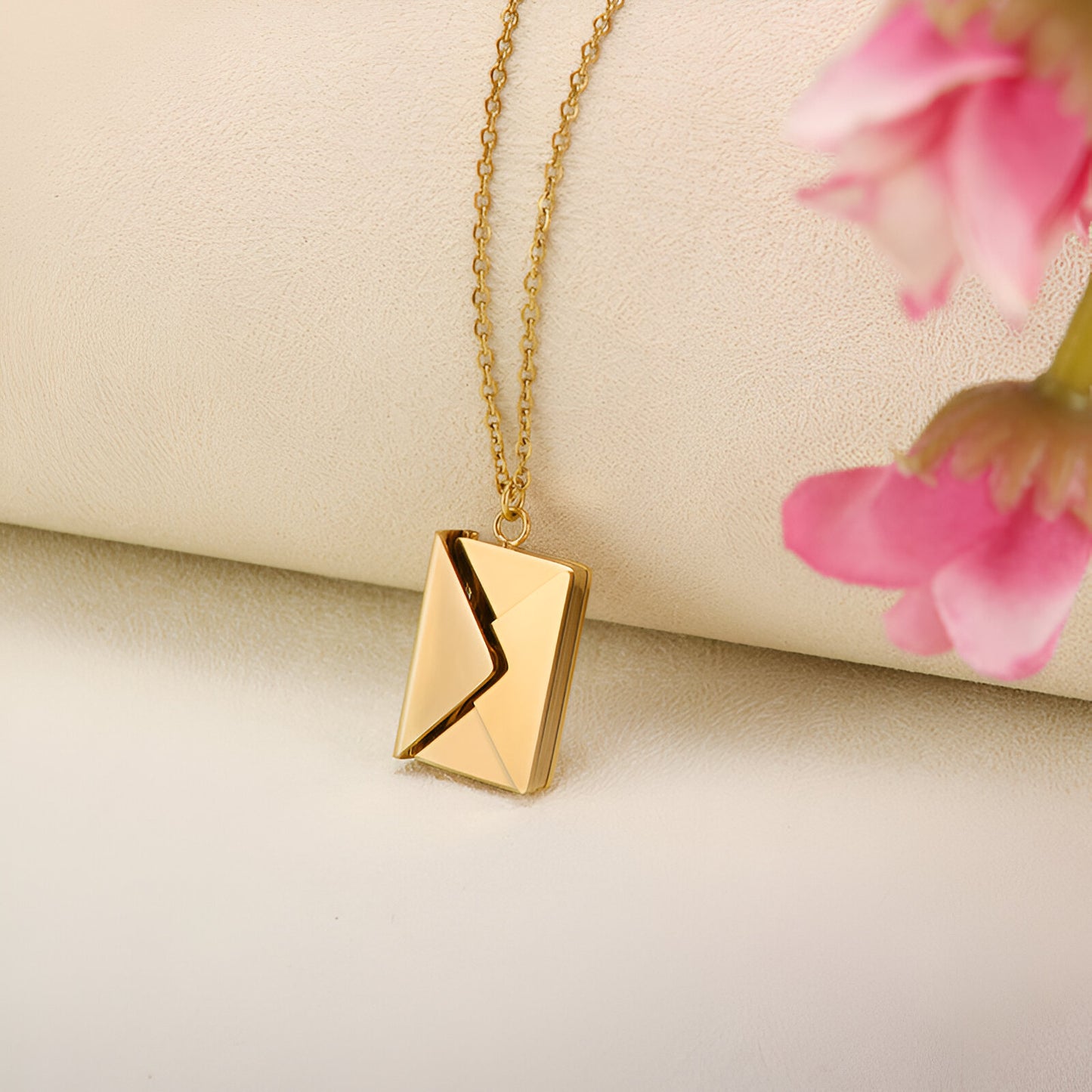 A gold chain necklace with an envelope-shaped pendant.