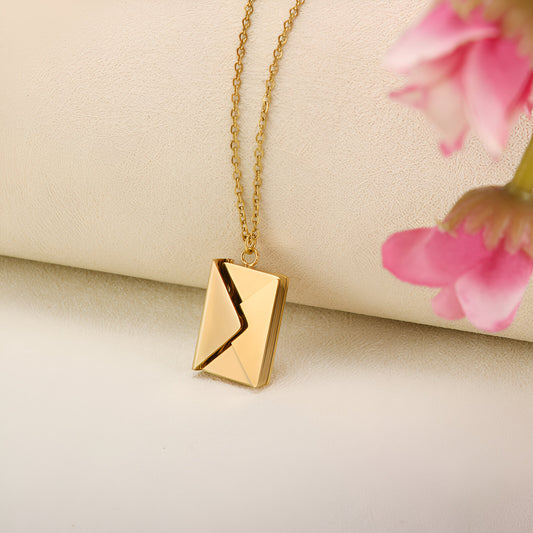 A gold chain necklace with an envelope-shaped pendant.