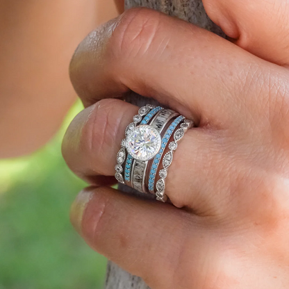 Silver rings embellished with stones and turquoise colored designs on a woman's ring finger.