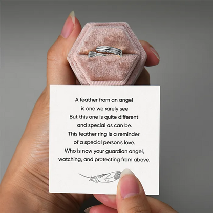 A silver feather-designed ring inside a pink velvet ring box and an inspirational message card.