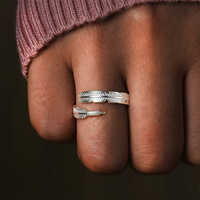 Silver feather-designed ring on a woman's ring finger.